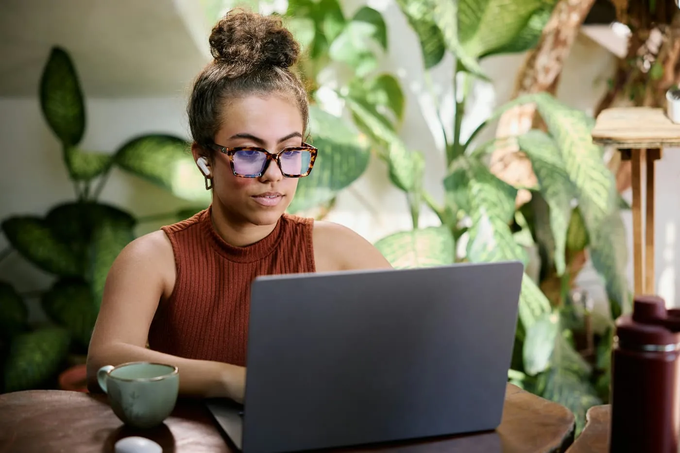 Professional working remotely on a laptop surrounded by plants